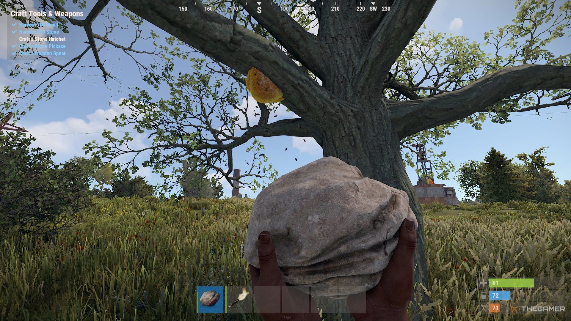 Rust stone holding a stone with both hands. There's a tree infront of him with the honeycomb hanging on a branch. In the background, there is a structure.