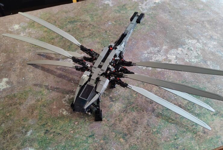 The Lego Dune Atreides Royal Ornithopter set with wings outstretched, sat on a grassy mat