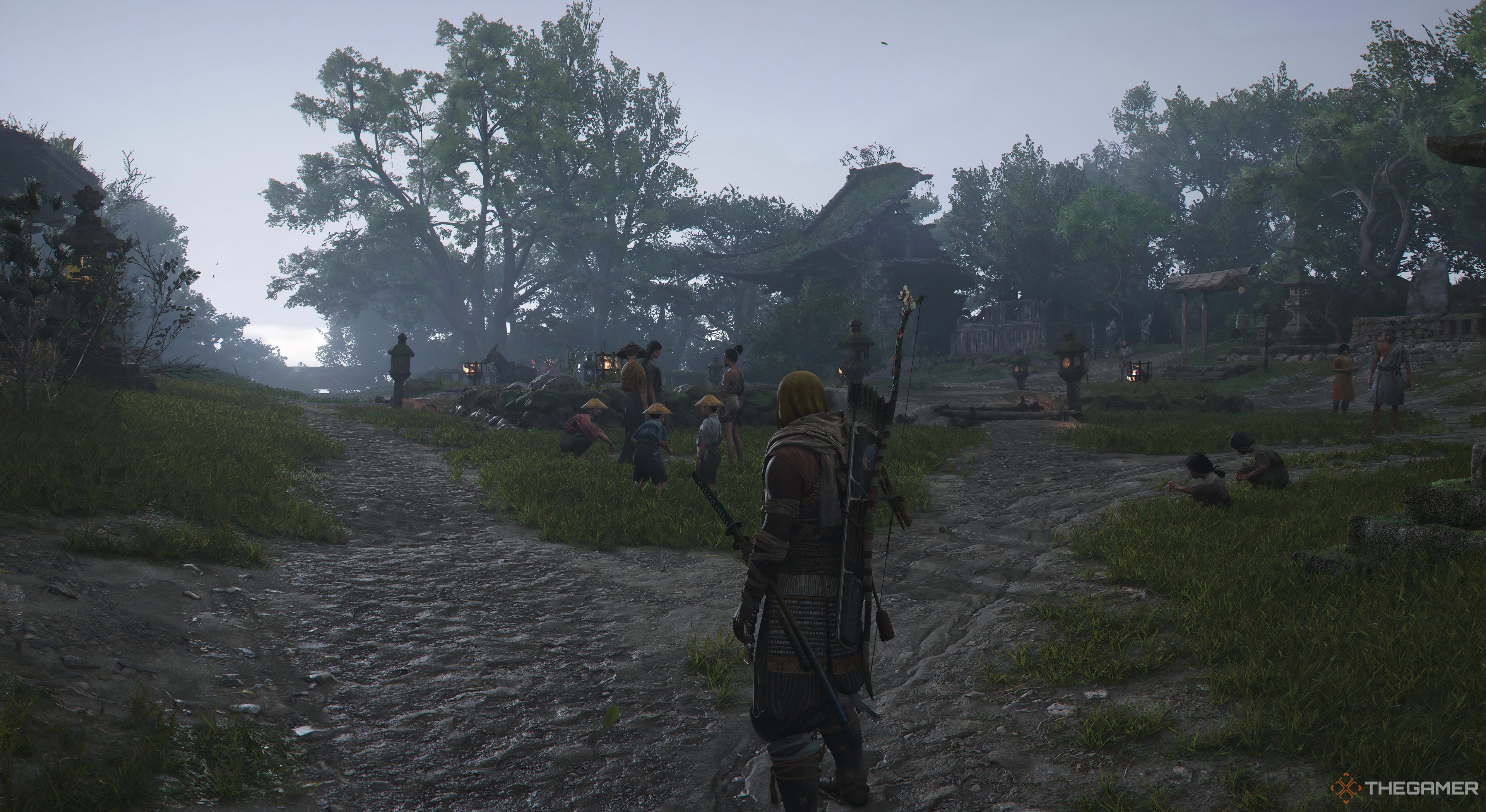 Assassin's Creed Shadow Yaskue looking at villagers. There is ruined shrine in the distance. The sun is coming up so the sky looks bright.