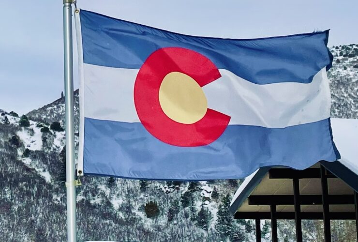 Colorado Flag flying in Glenwood Springs, CO, with mountains in the background