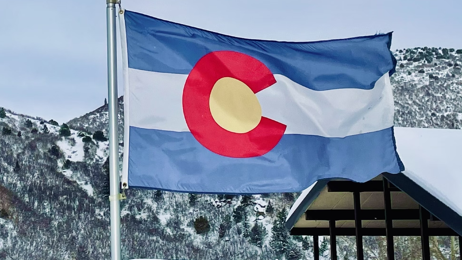 Colorado Flag flying in Glenwood Springs, CO, with mountains in the background